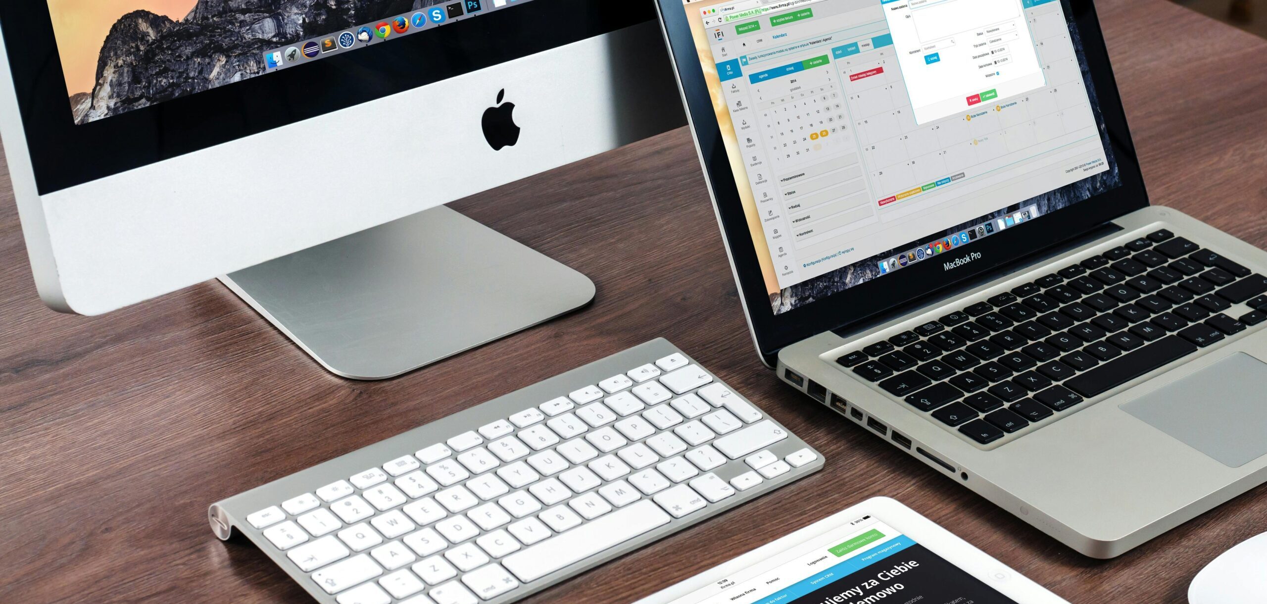Image of a laptop, a desktop monitor, and a tablet on a desk from an angel.